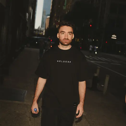 Oliver Heldens in a black Heldeep t-shirt on a city street at night